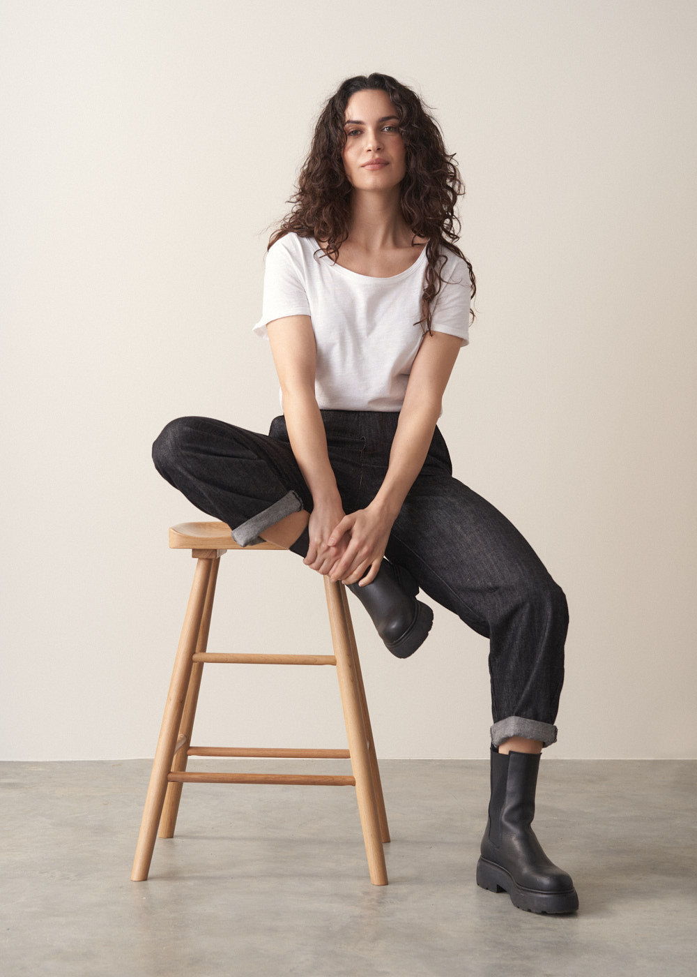Woman wearing grey jumper and dark blue black straight leg denim jeans