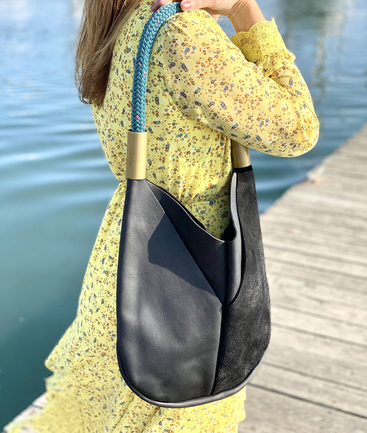 Black leather tote with teal dock line over the shoulder