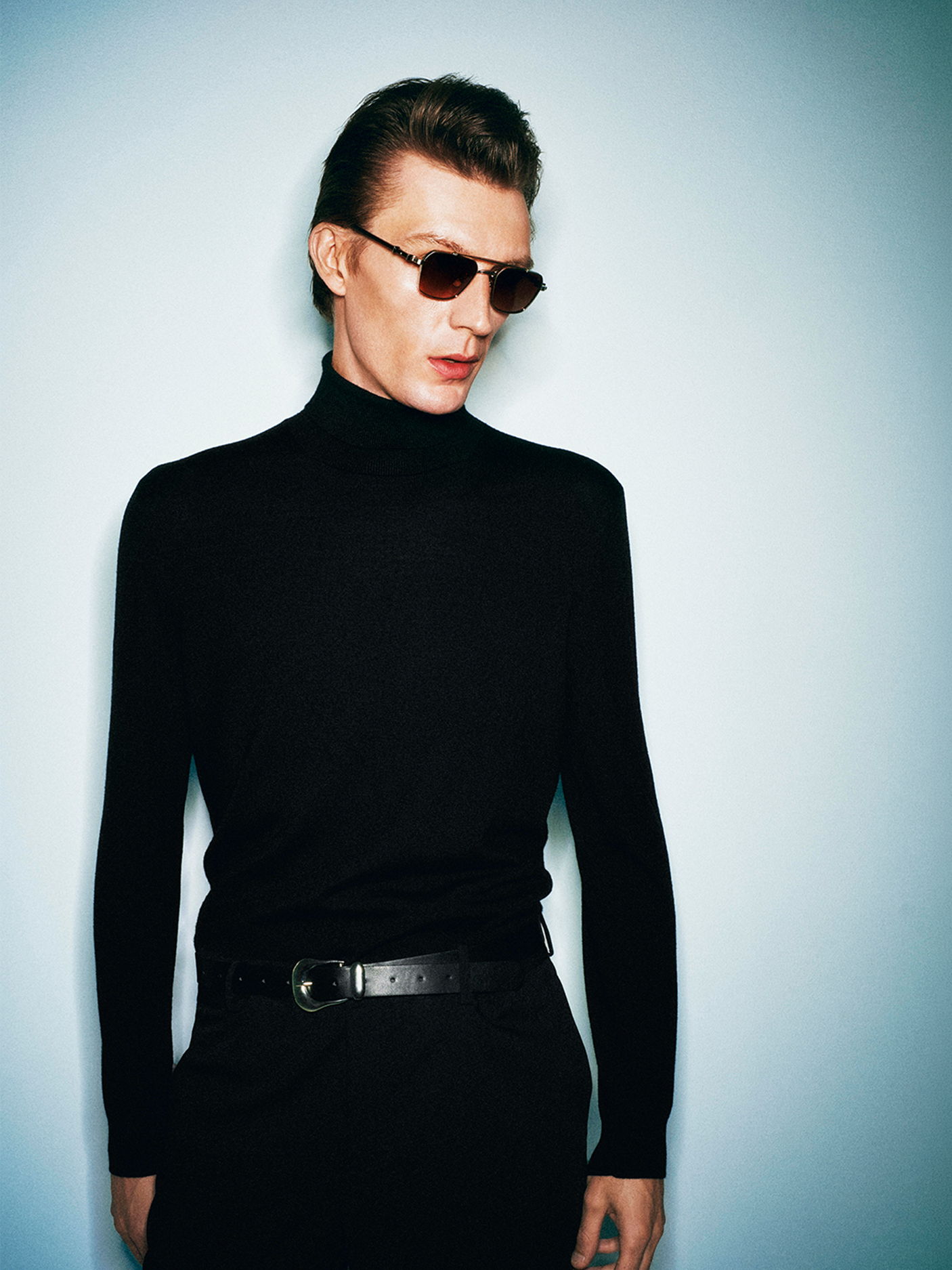 A person in Robert Marc sunglasses wearing a black turtleneck against a light background.