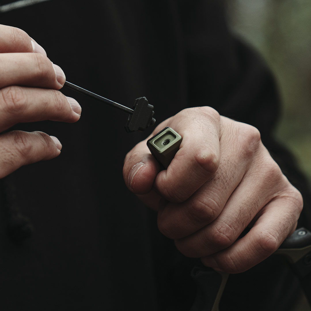 Person holding a small object and a string in a forested background.