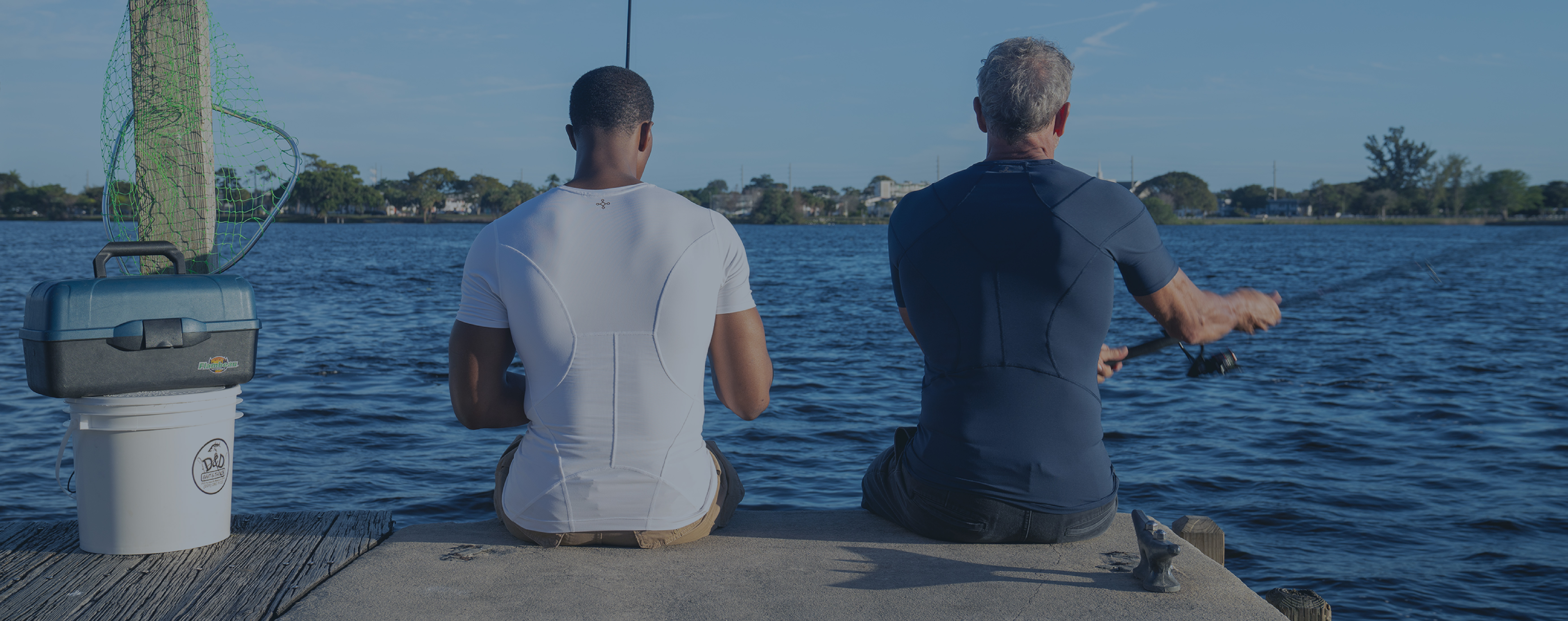 Two men fishing wearing Tommie Copper support shirts