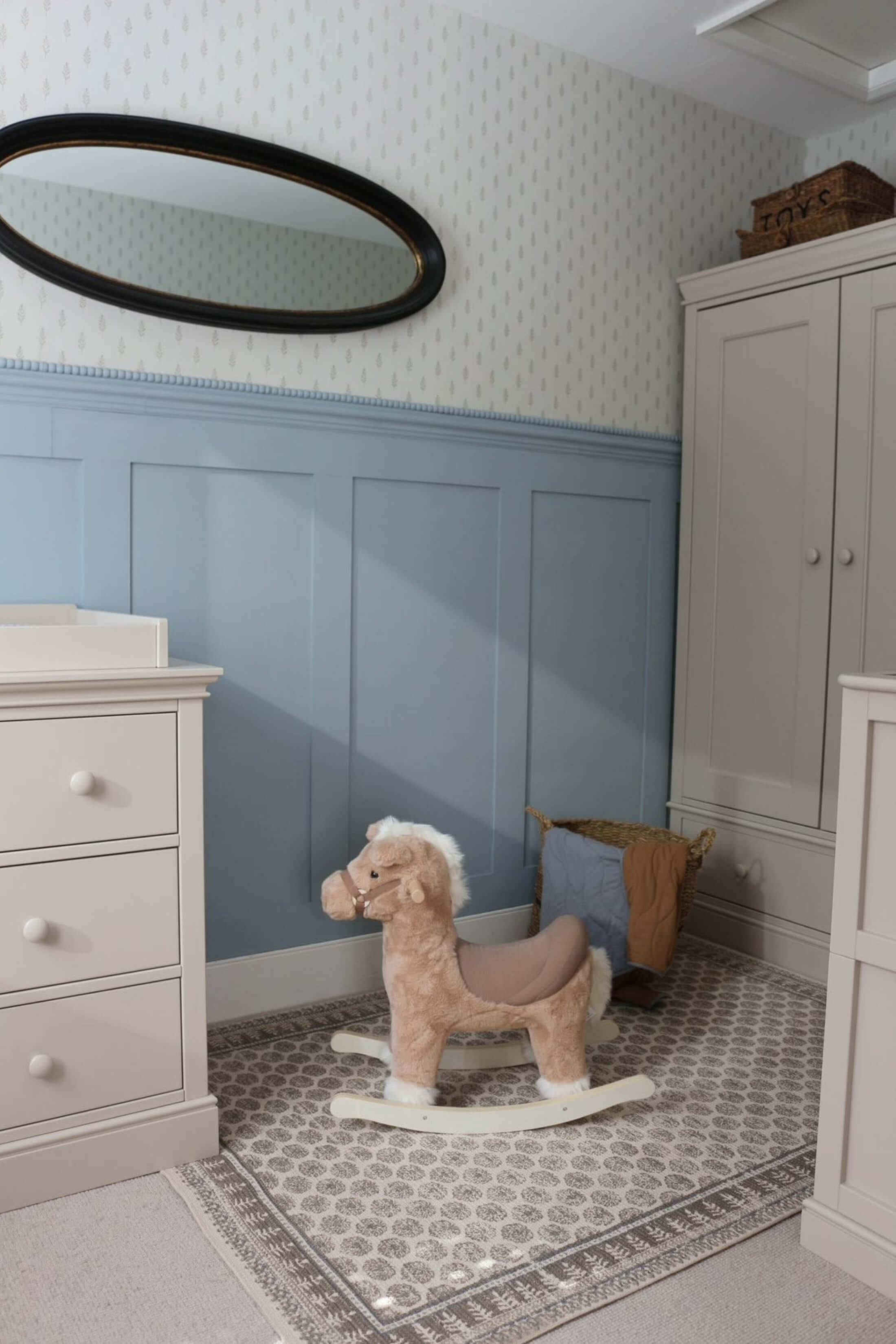 A children's room with a rocking horse, dresser, and mirror.