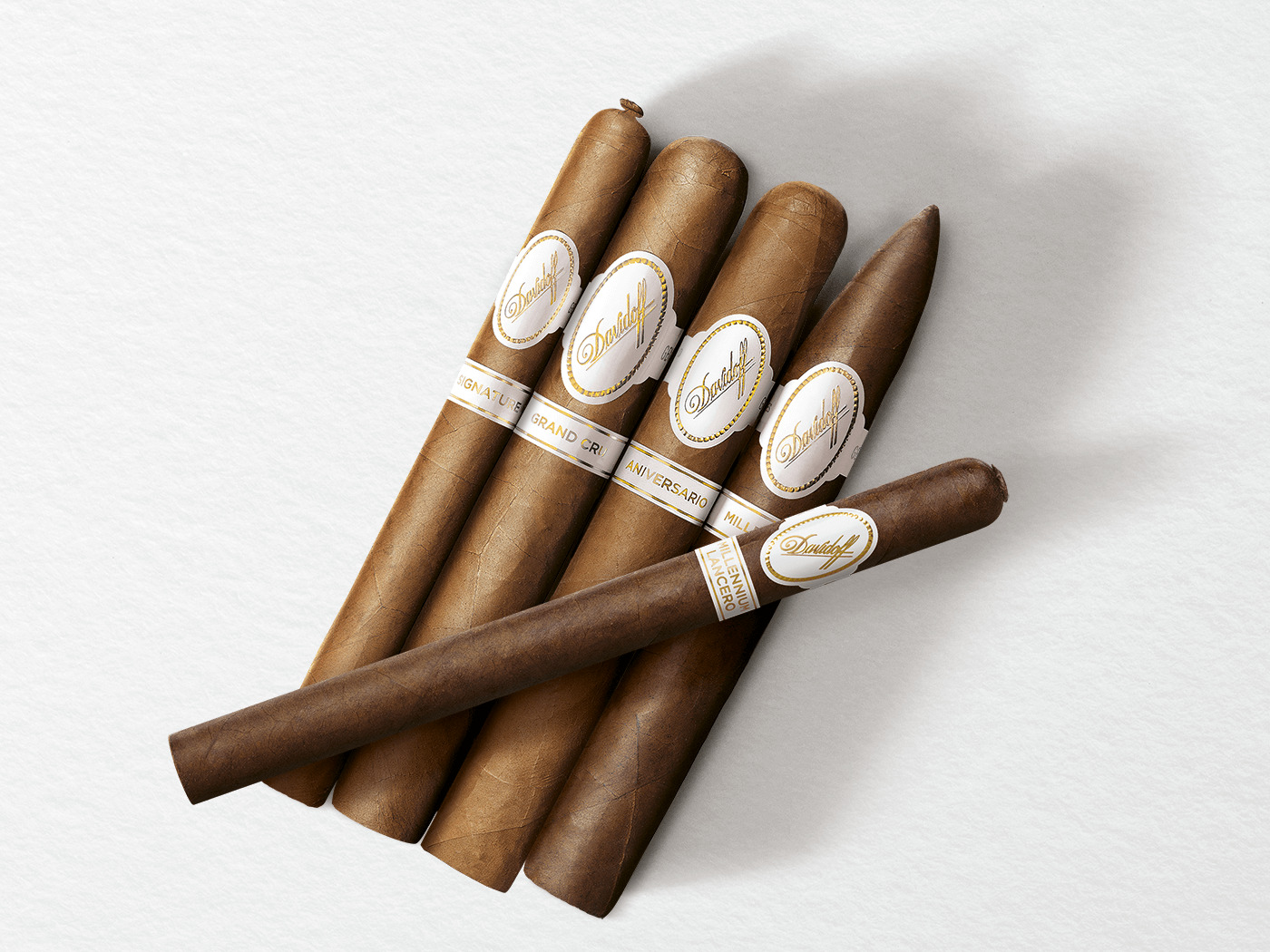 4 Zigarren der Davidoff White Band Collection Linien Signature, Grand Cru, Millennium und Aniversario mit einer Davidoff Millennium Lancero Limited Edition Collection Zigarre quer drüberliegend. 