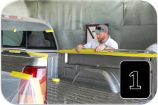 Technician masking the edges of a truck bed before spray-on bedliner application