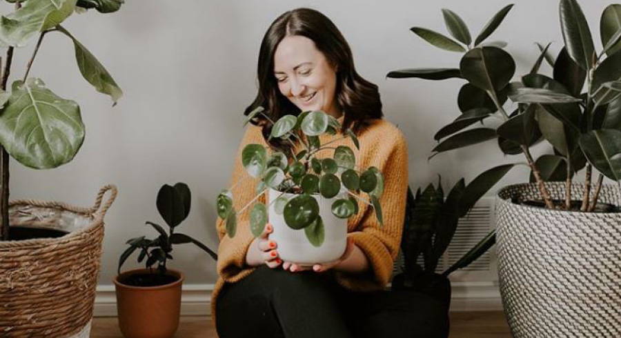 Dark haired woman holding a potted plant.