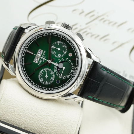 A silver watch with a green dial and black leather strap on display.