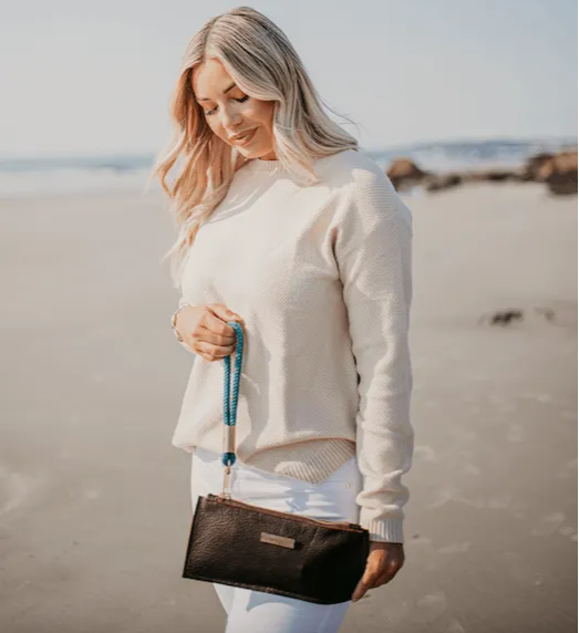 woman holding teal wrist strap on brown bag