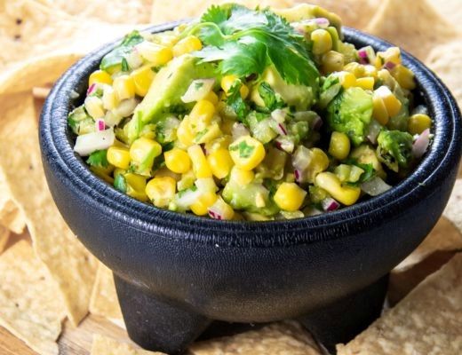 Bowl of corn salad with herbs, served with tortilla chips.