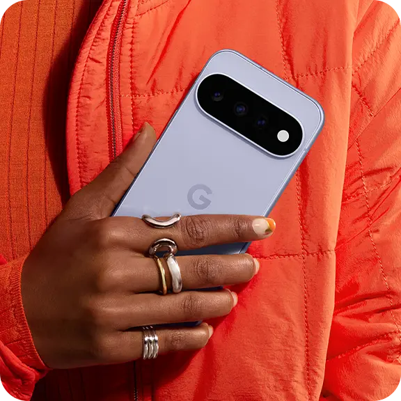 Person holding a Google phone, wearing rings, against an orange background.
