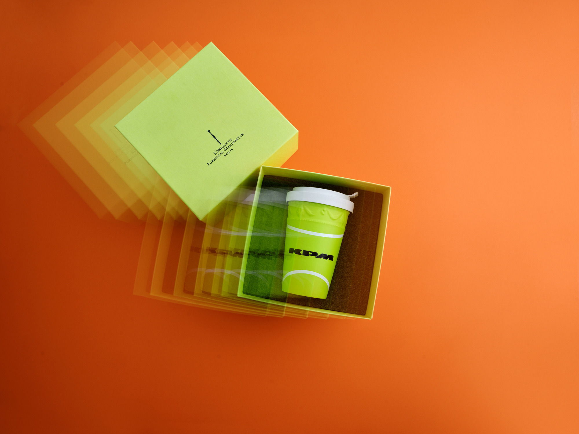 A green cup inside a box on an orange background.