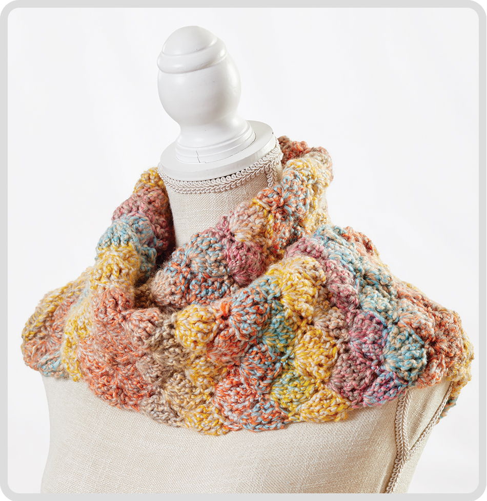 Colorful knitted scarf displayed on a dress form.