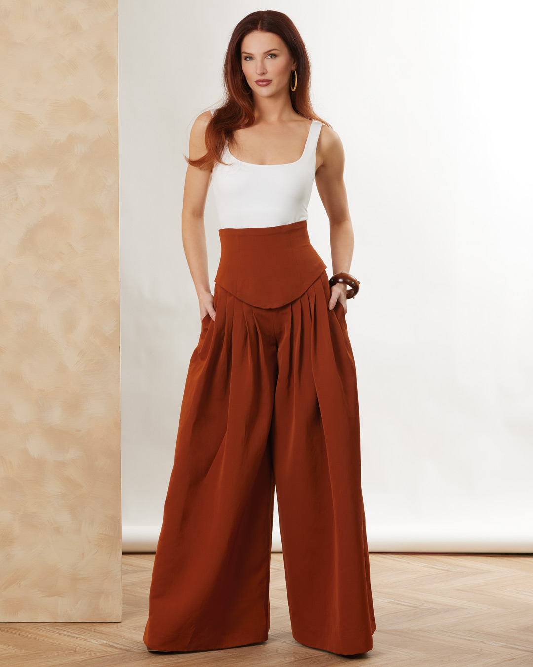 A woman wearing a white top and brown wide-legged pants.