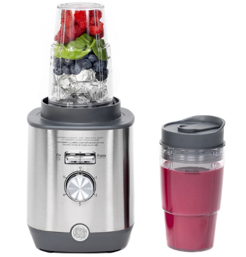 A blender with fruits and a smoothie cup.