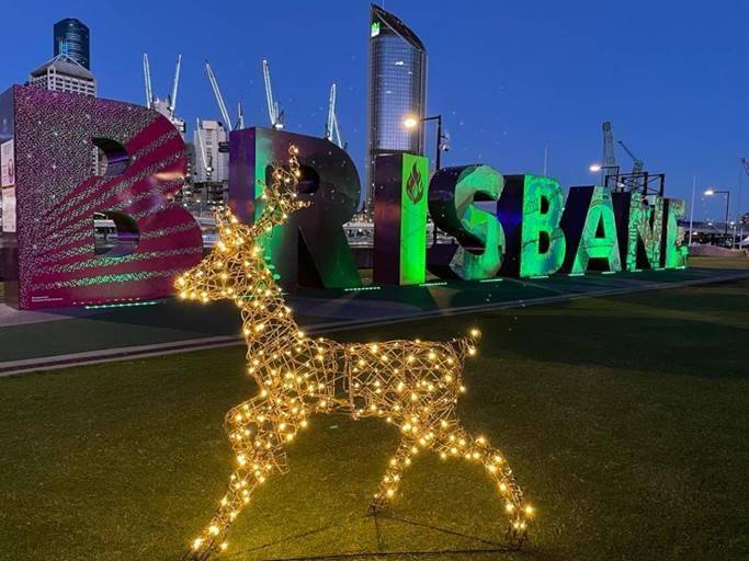 Stag light up reindeer in front of the lit up Brisbane sign at night. 