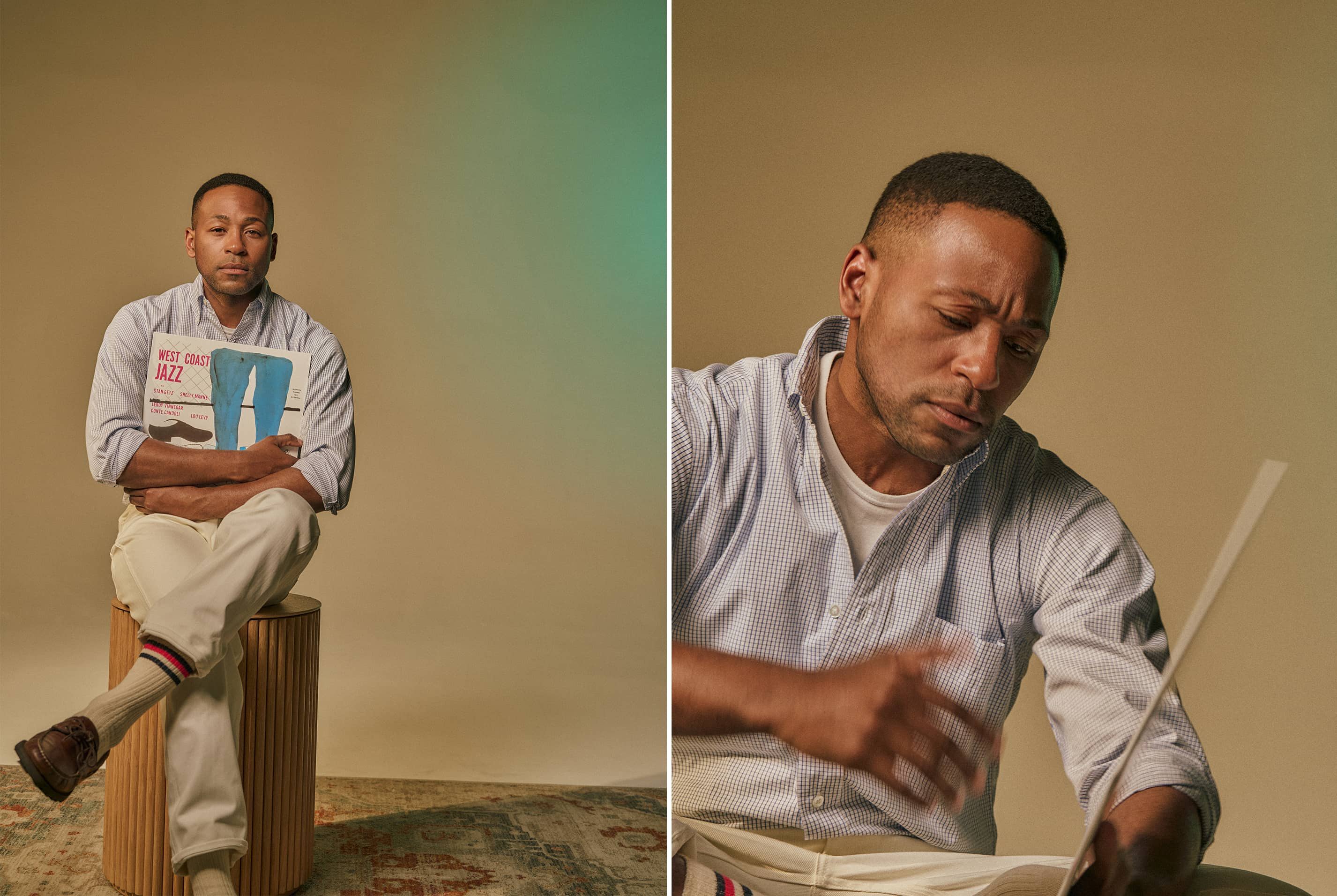 Man sitting on a stool, reading a book with a neutral background.