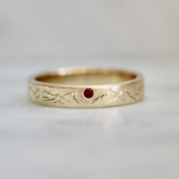 Hand-engraved wedding band with mountains and a ruby