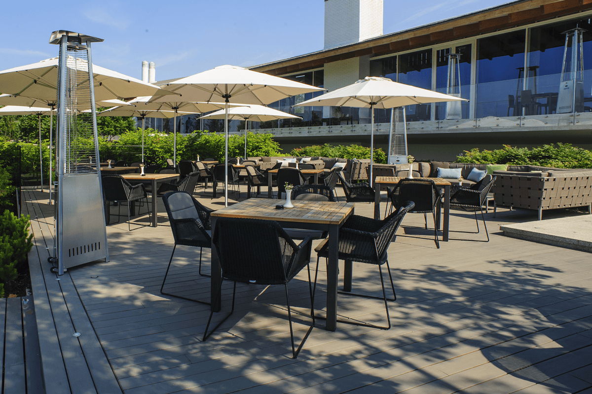 Commercial restaurant patio furniture with outdoor dining tables, woven chairs, umbrellas and patio heaters