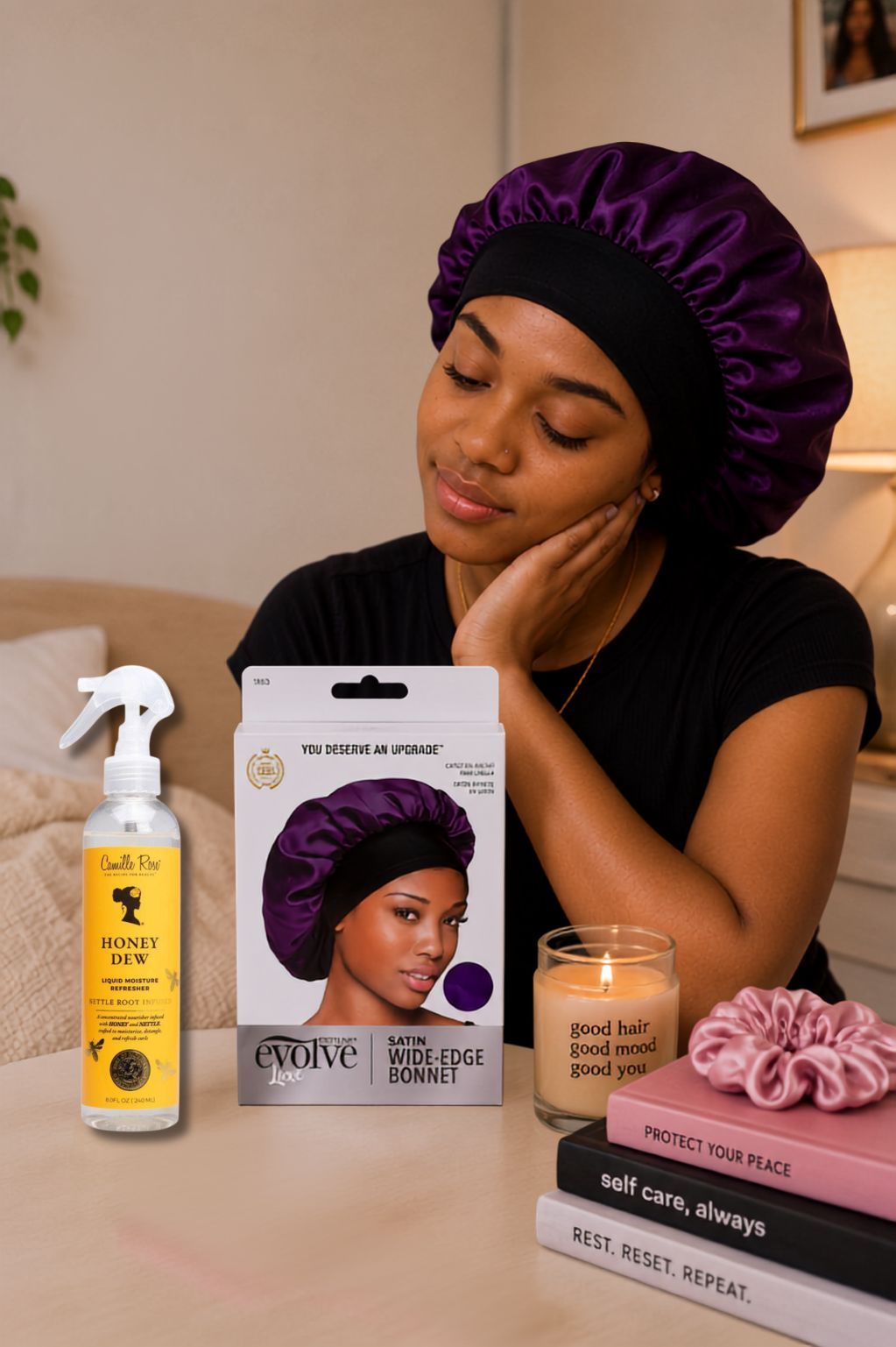 Woman wearing a purple satin bonnet, with hair products and a candle nearby.