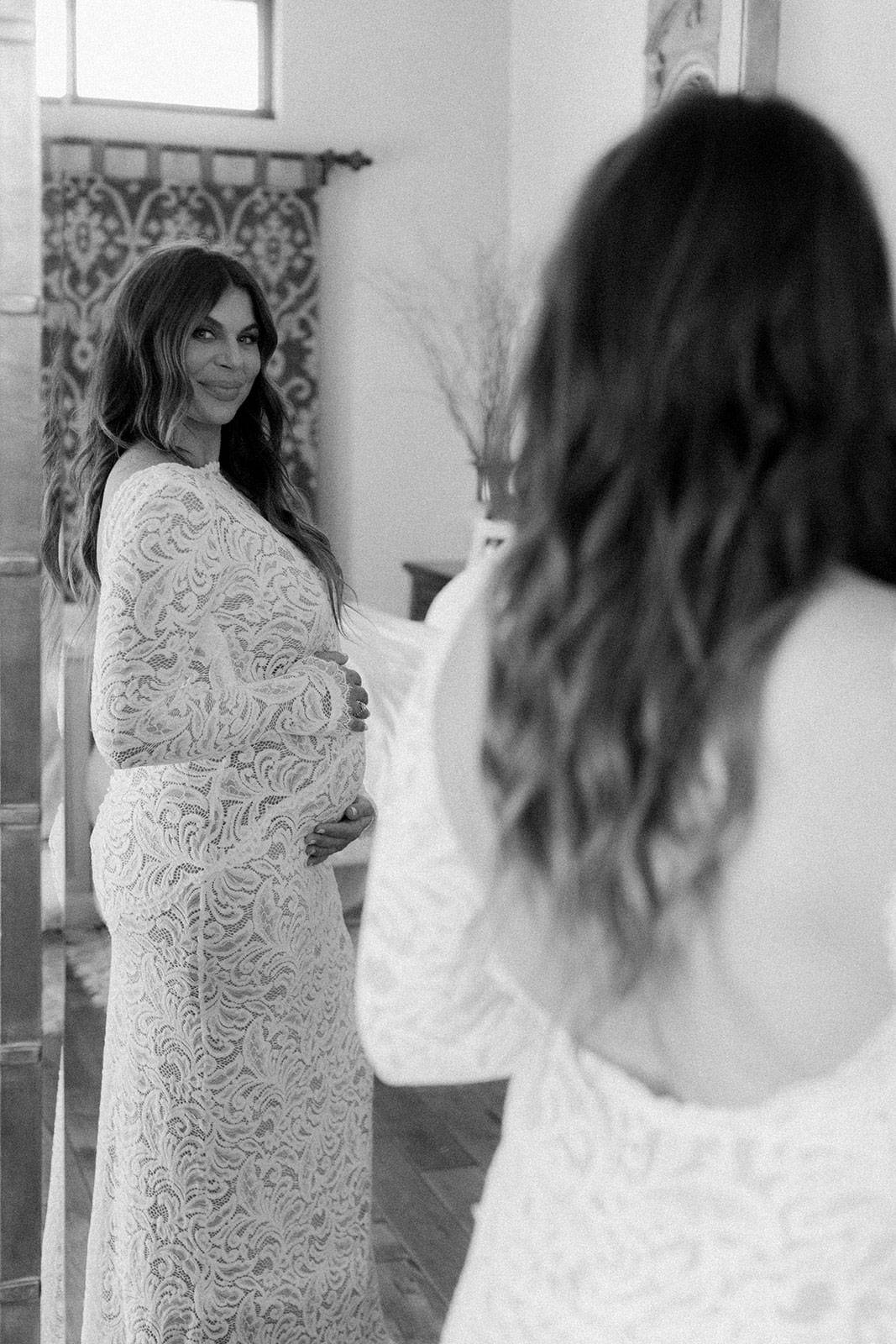 Die Braut schaut in den Spiegel und hält den Babybauch