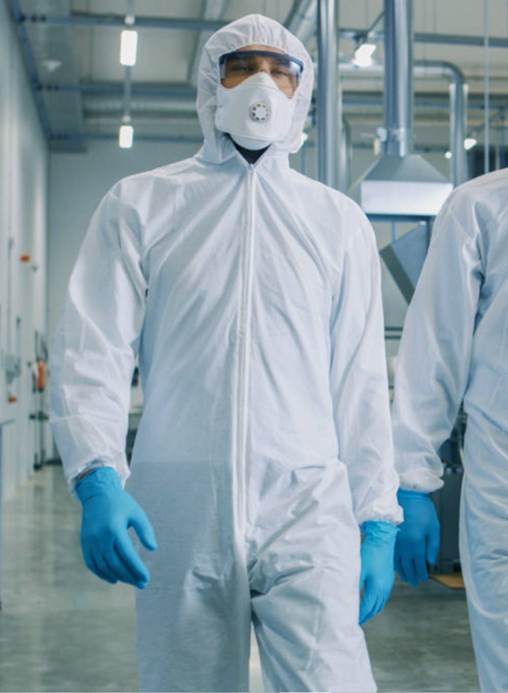 Lab technician wearing disposable coveralls, an N95 mask, disposable nitrile gloves and safety glasses.