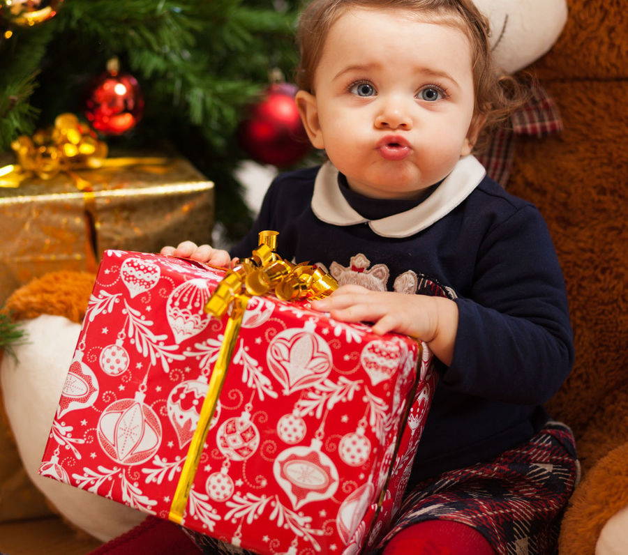 Un bebé abre su regalo de navidad, una canastilla con lo esencial para su cuidado