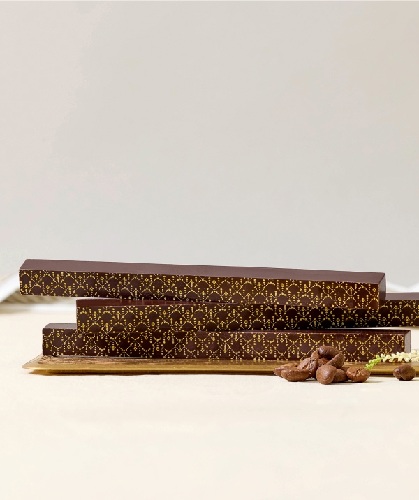 Three chocolate bars with decorative packaging on a neutral background.