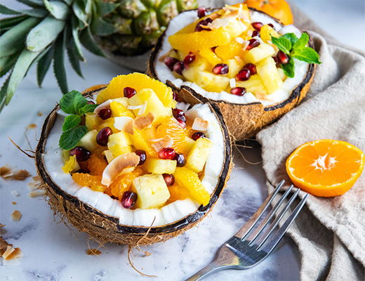 Coconut bowls filled with tropical fruit and garnished with mint leaves.