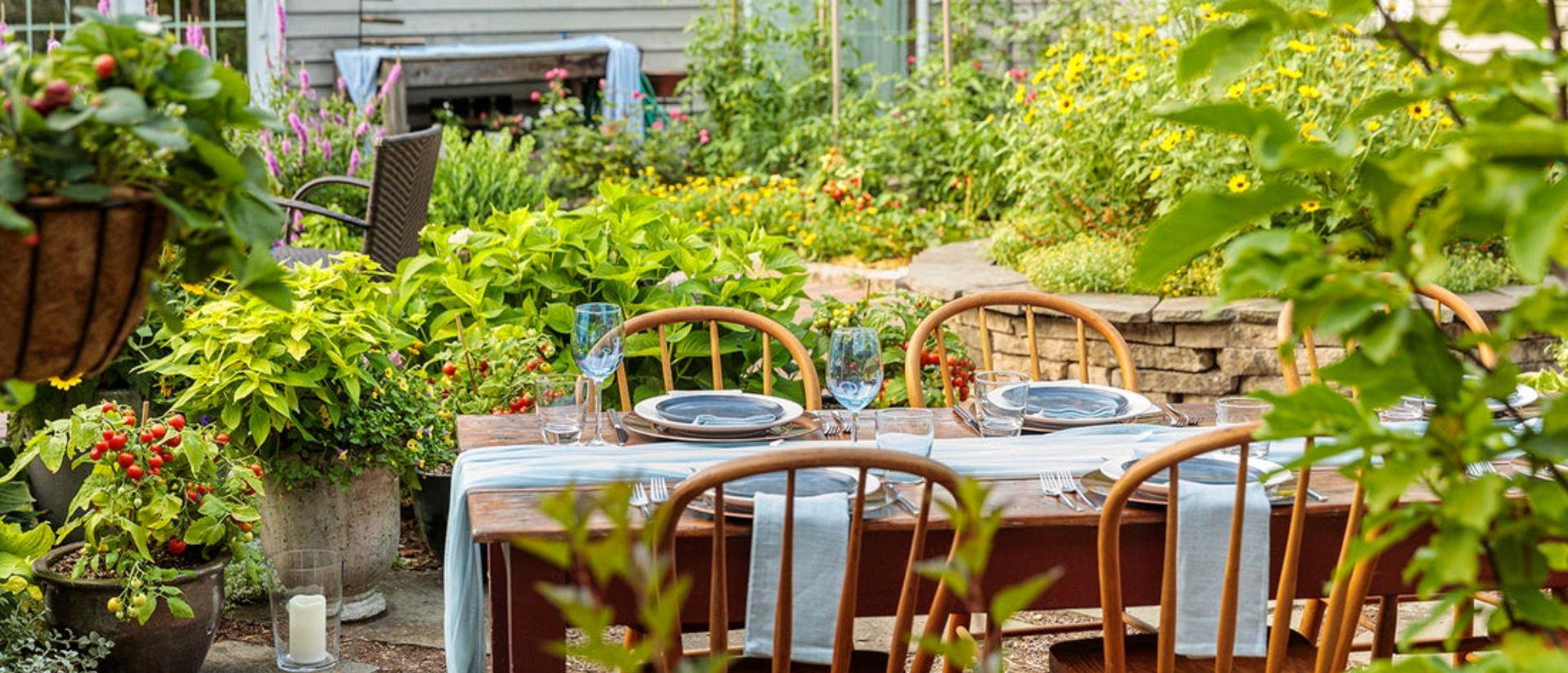 Dinner table and chair set up in the backyard surrounded by veggie garden