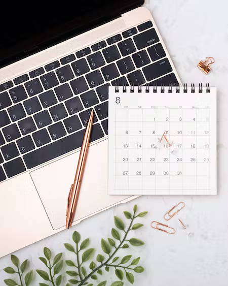 laptop with calendar and pens on table