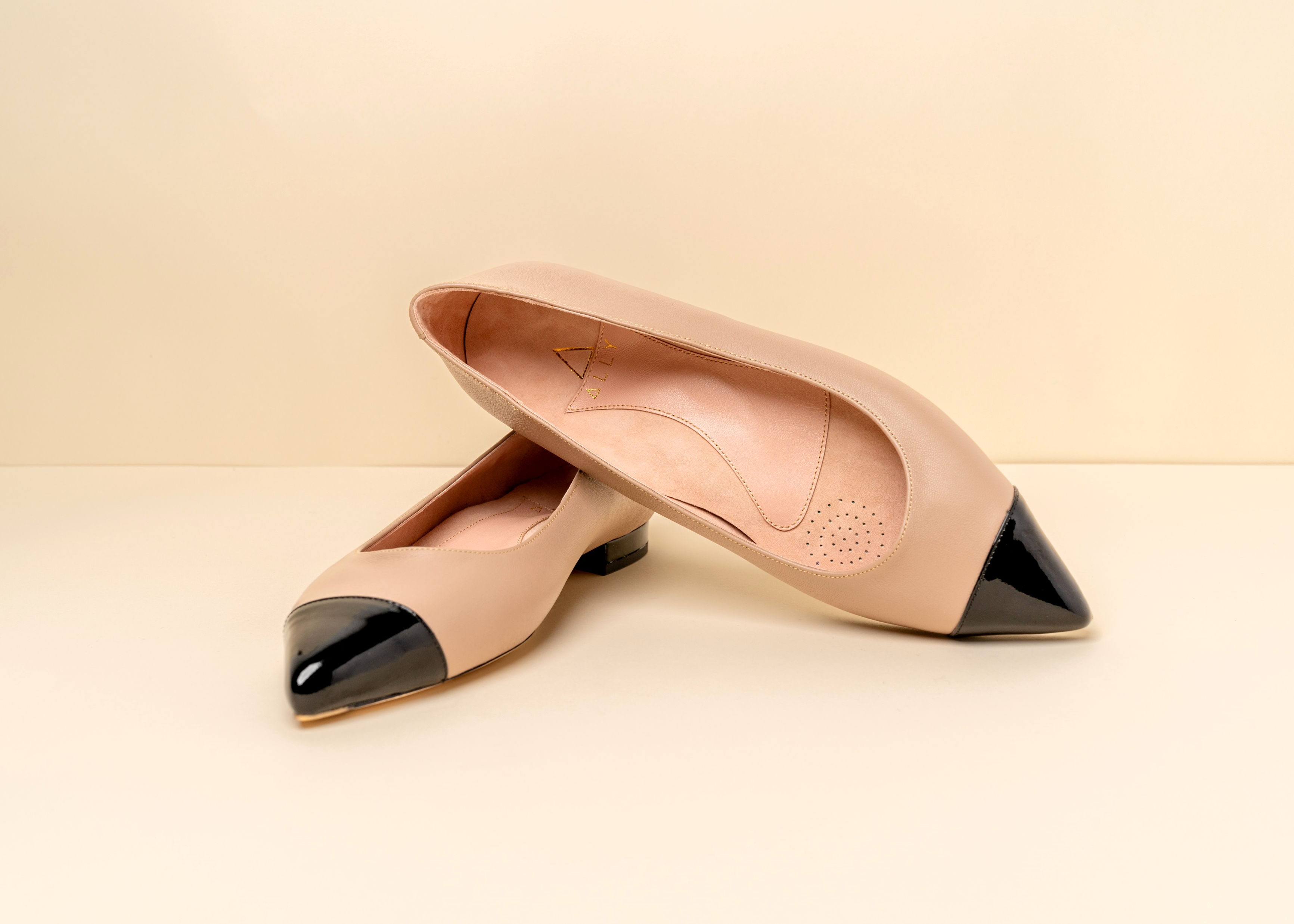 Beige ballet flat with a black toe cap.
