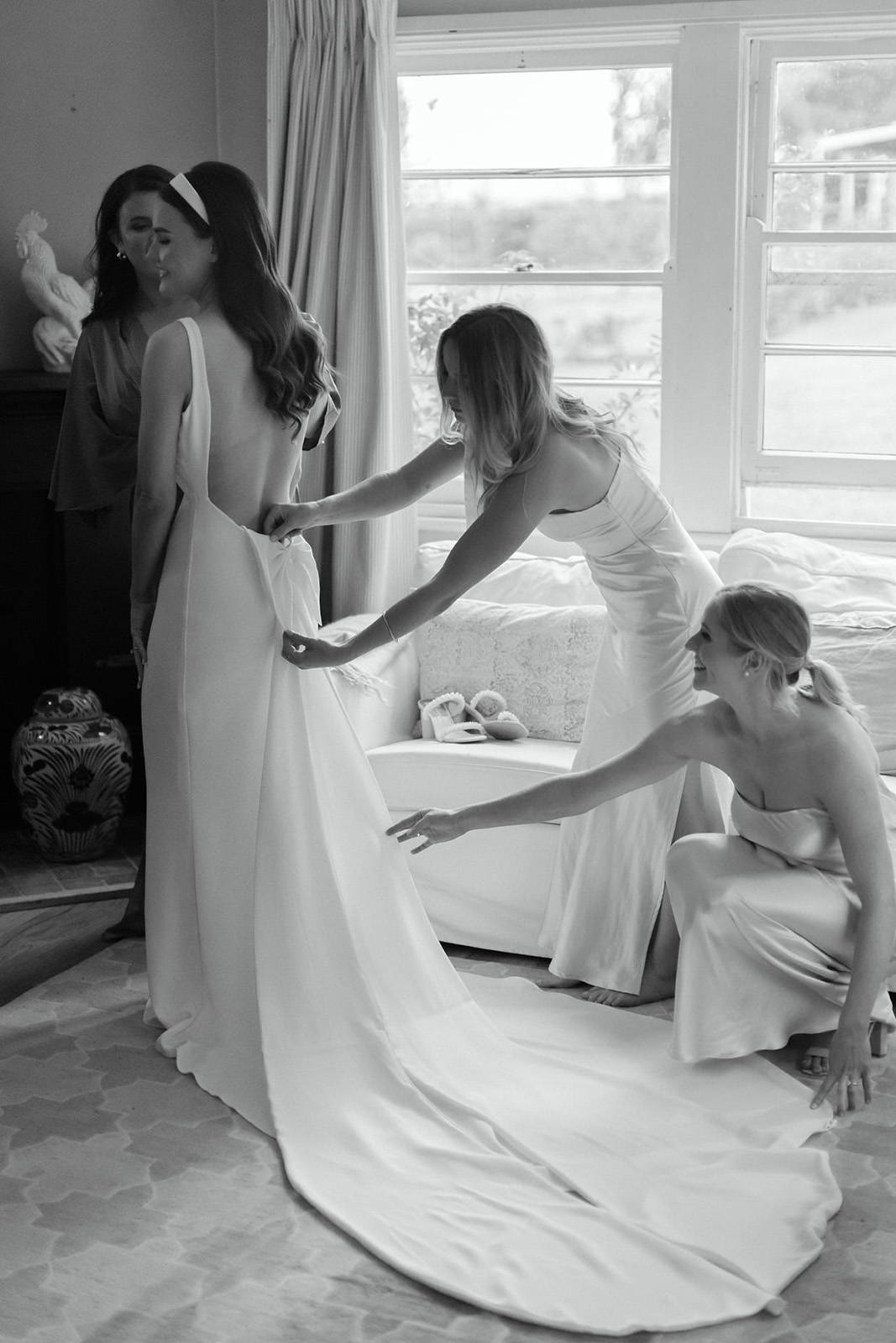 Bridesmaids helping the Bride with her dress