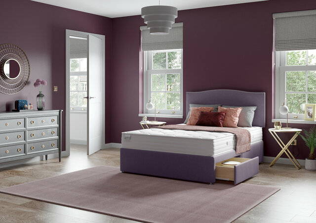Wide view of a lilac toned bedrooms with lilac divan bed set. A large drawer is open in the side of the divan.