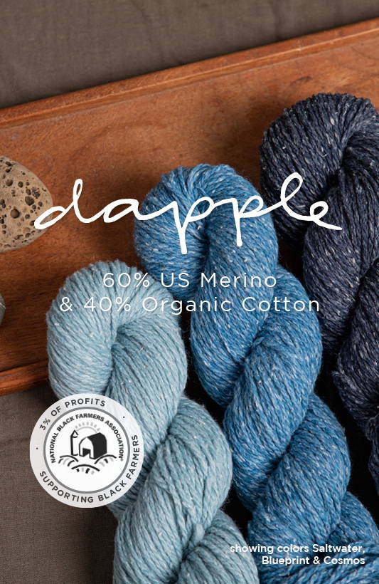 Three skeins of cotton  & wool blended yarn in three shades of blues sit on a dark linen fabric with a wooden tray and two small rocks. The title over the image reads “Dapple / 60% US Merino & 40% Organic Cotton” with and a badge that reads “3% of profits supporting black farmers” is in the lower left.