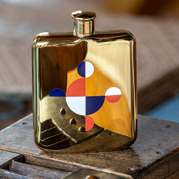 A shiny gold flask with a colorful geometric design.