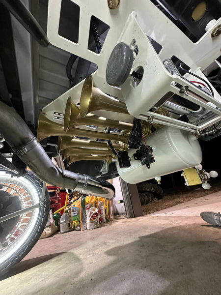 HornBlasters train horn kit with five brass trumpets and white air tank mounted on custom white bracket under vehicle