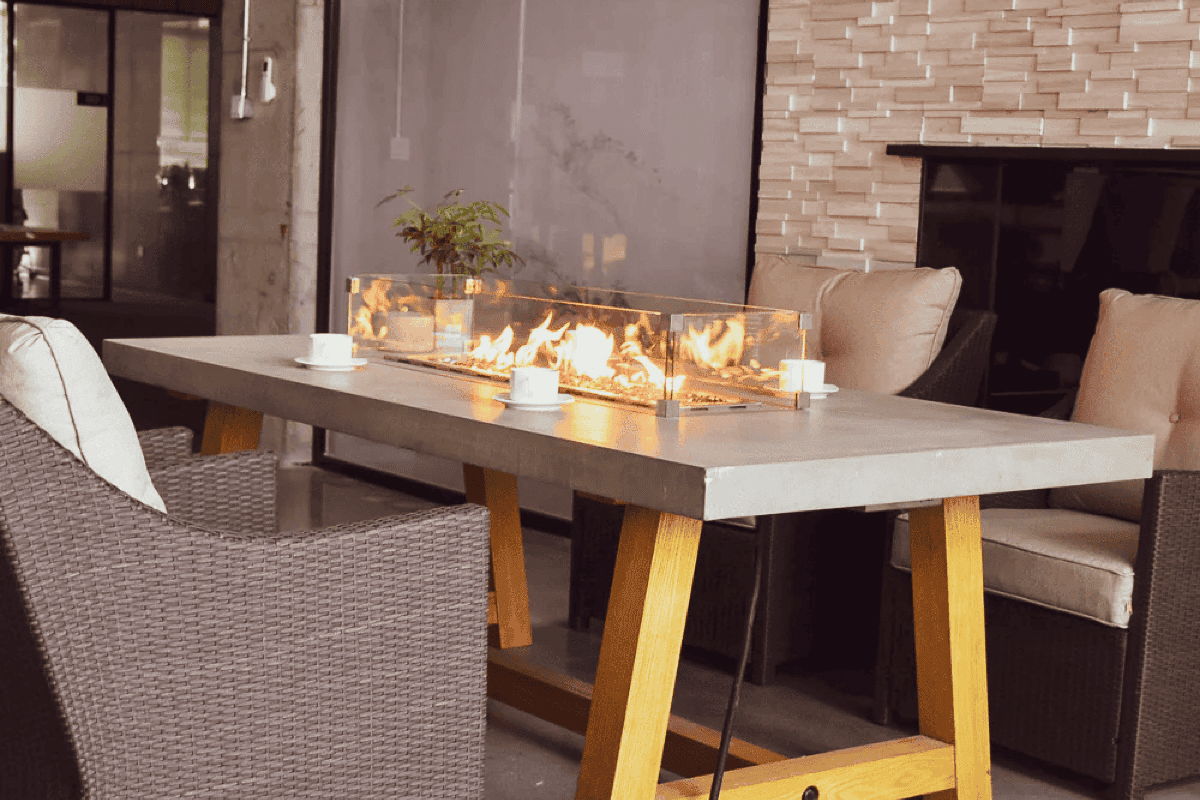 Outdoor dining fire table with cushioned chairs for a covered patio entertaining area.
