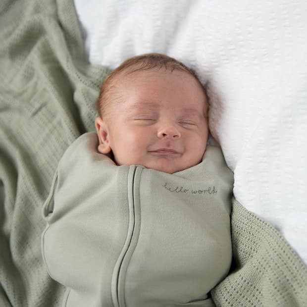 A sleeping baby swaddled in a light green blanket.