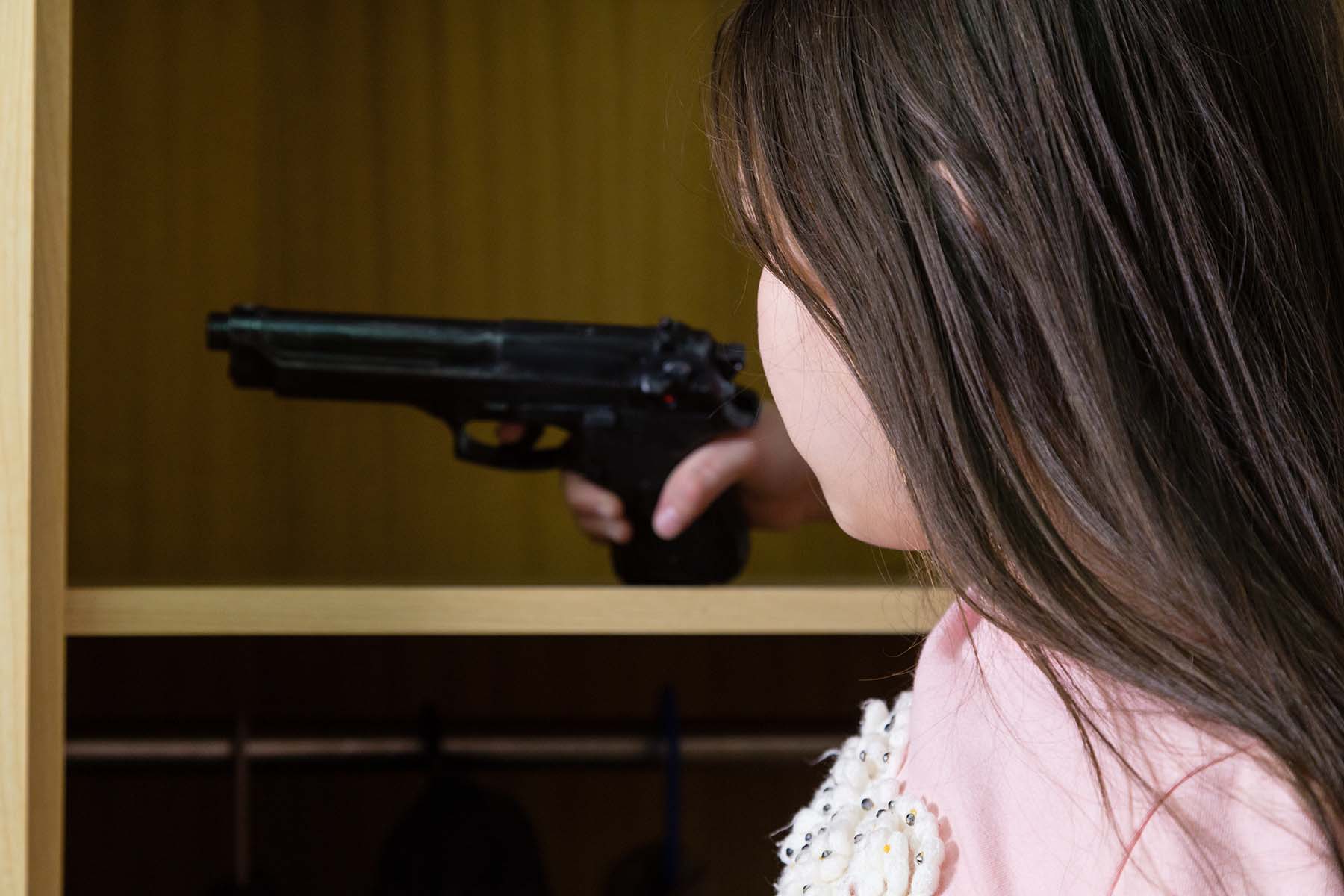 Little girl getting handgun out of closet