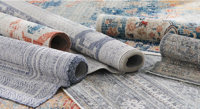 Various rolled area rugs displayed on a surface.