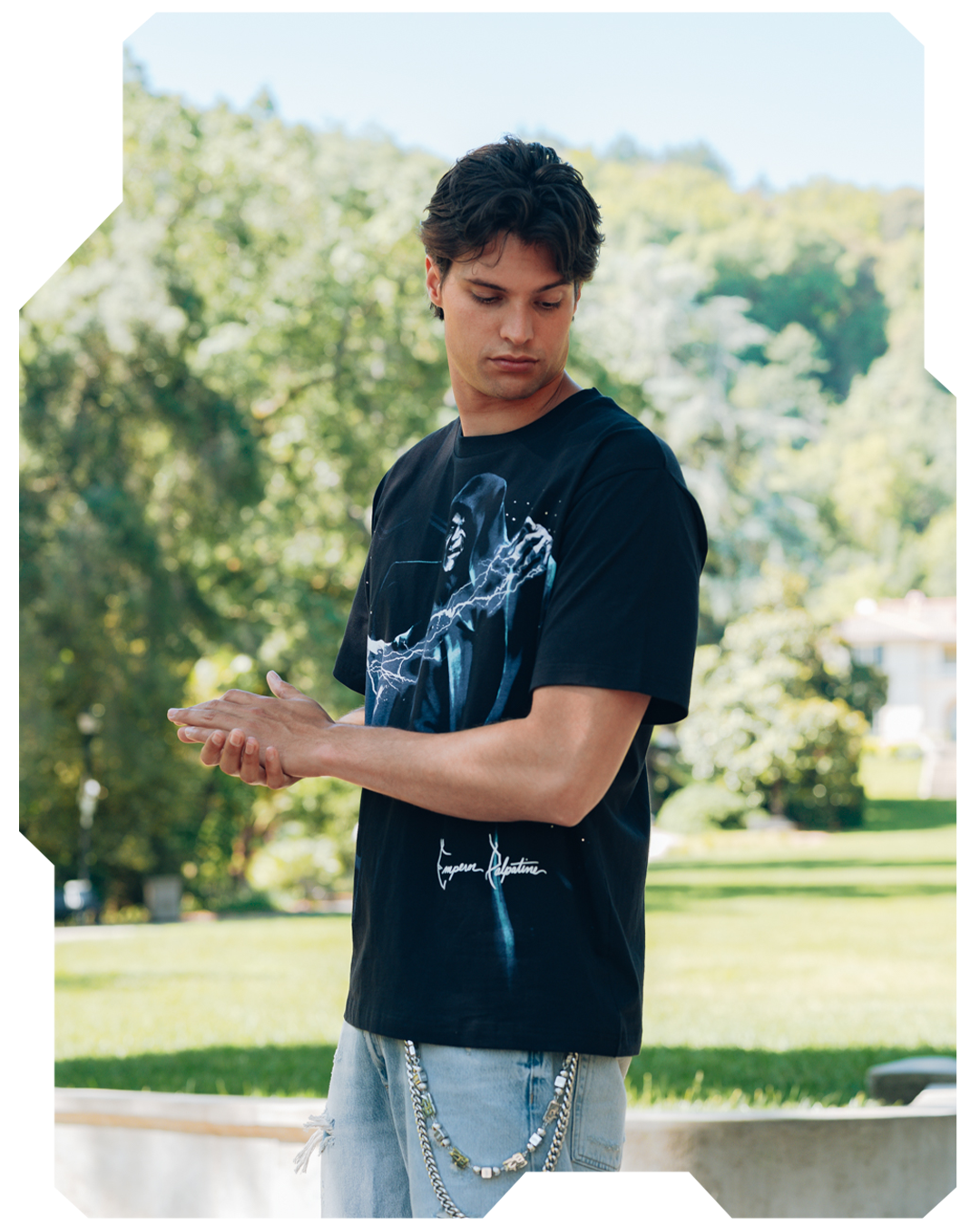 Young man in a black graphic t-shirt standing outdoors.