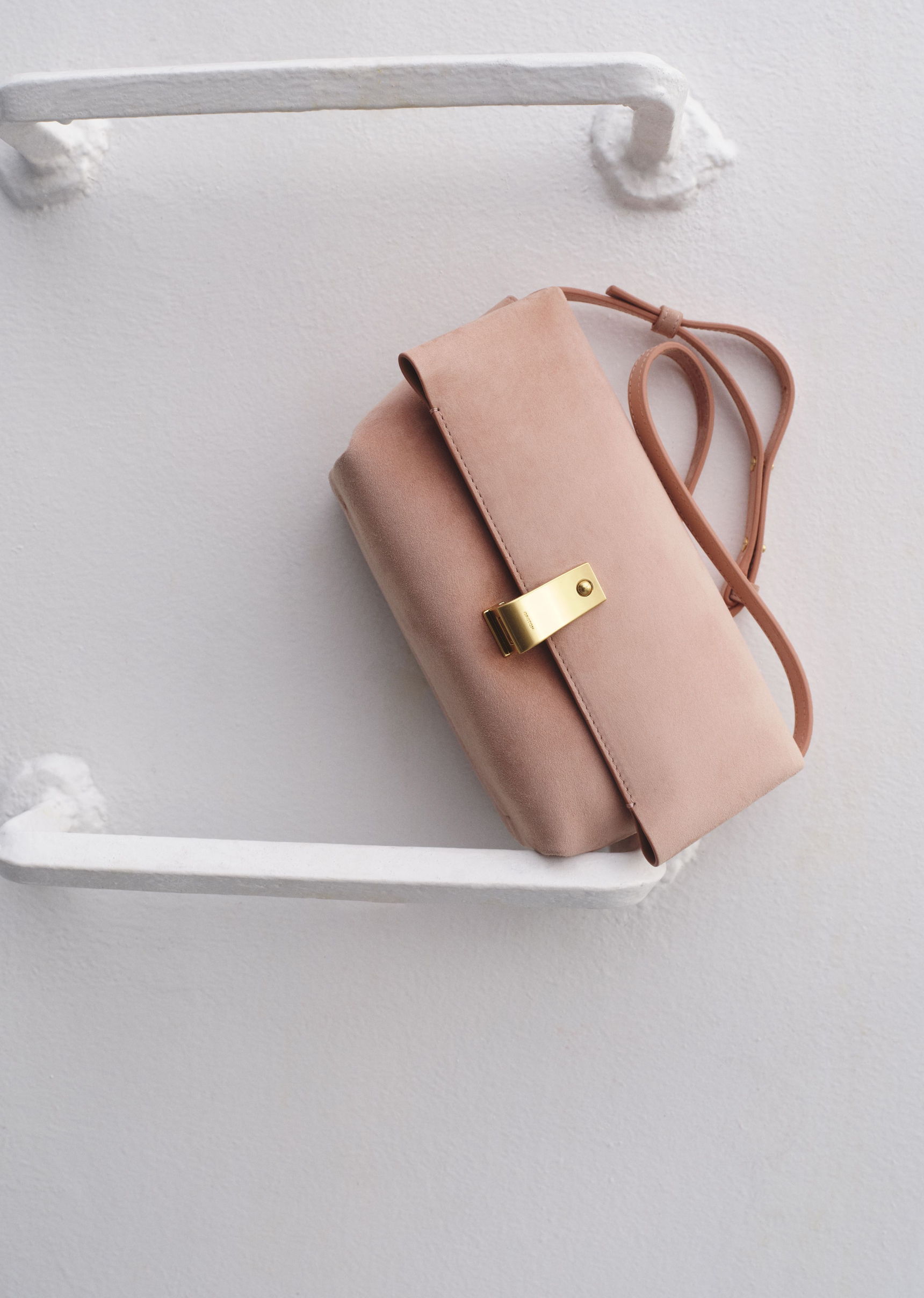 A pink handbag with a gold clasp on a white background.