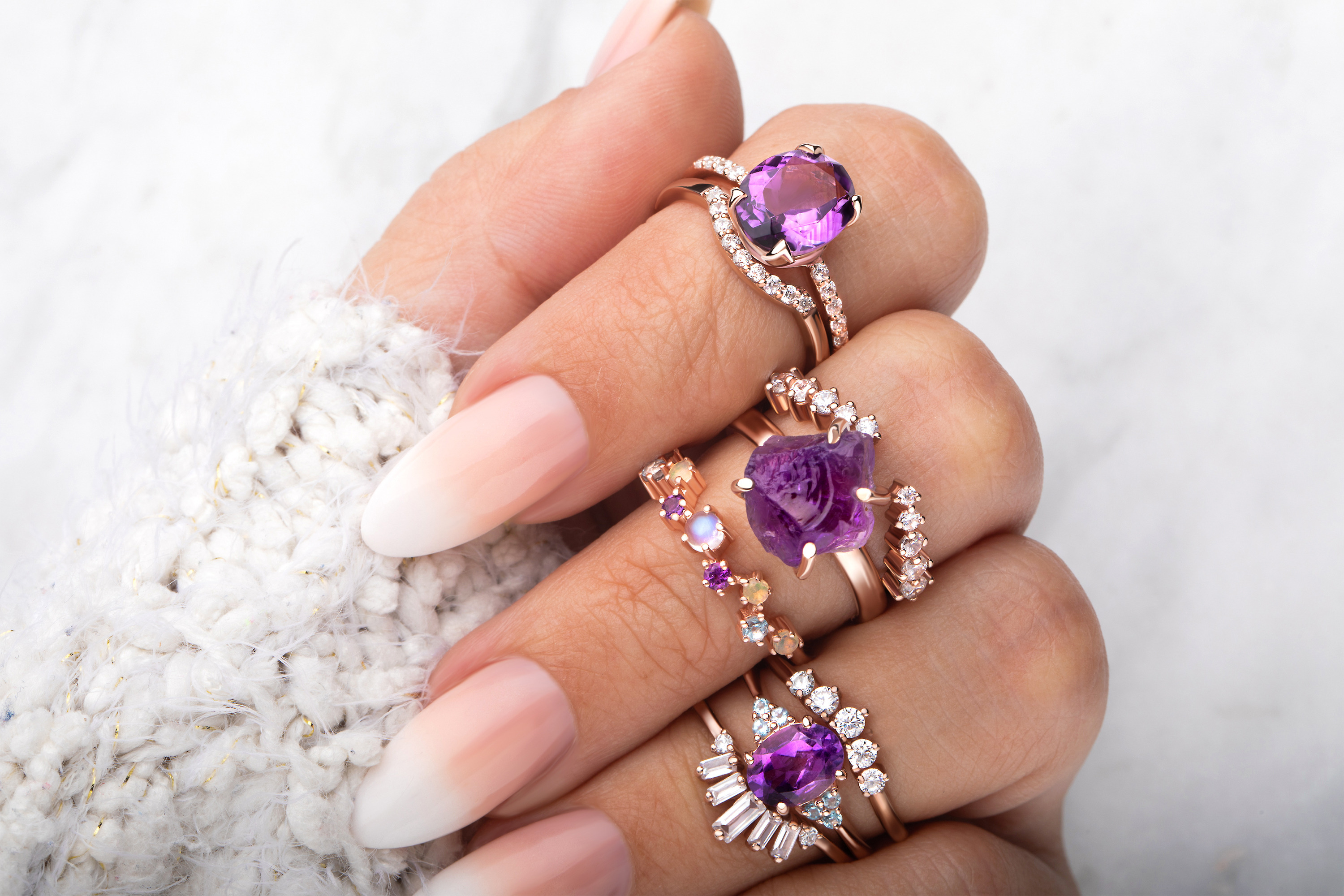 A woman is wearing different rings with Amethyst and other gemstones in 14kt Rose Gold Vermeil.