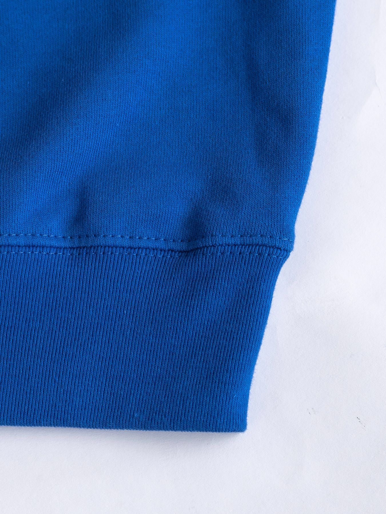 Close-up of a blue fabric sleeve with a hem detail.