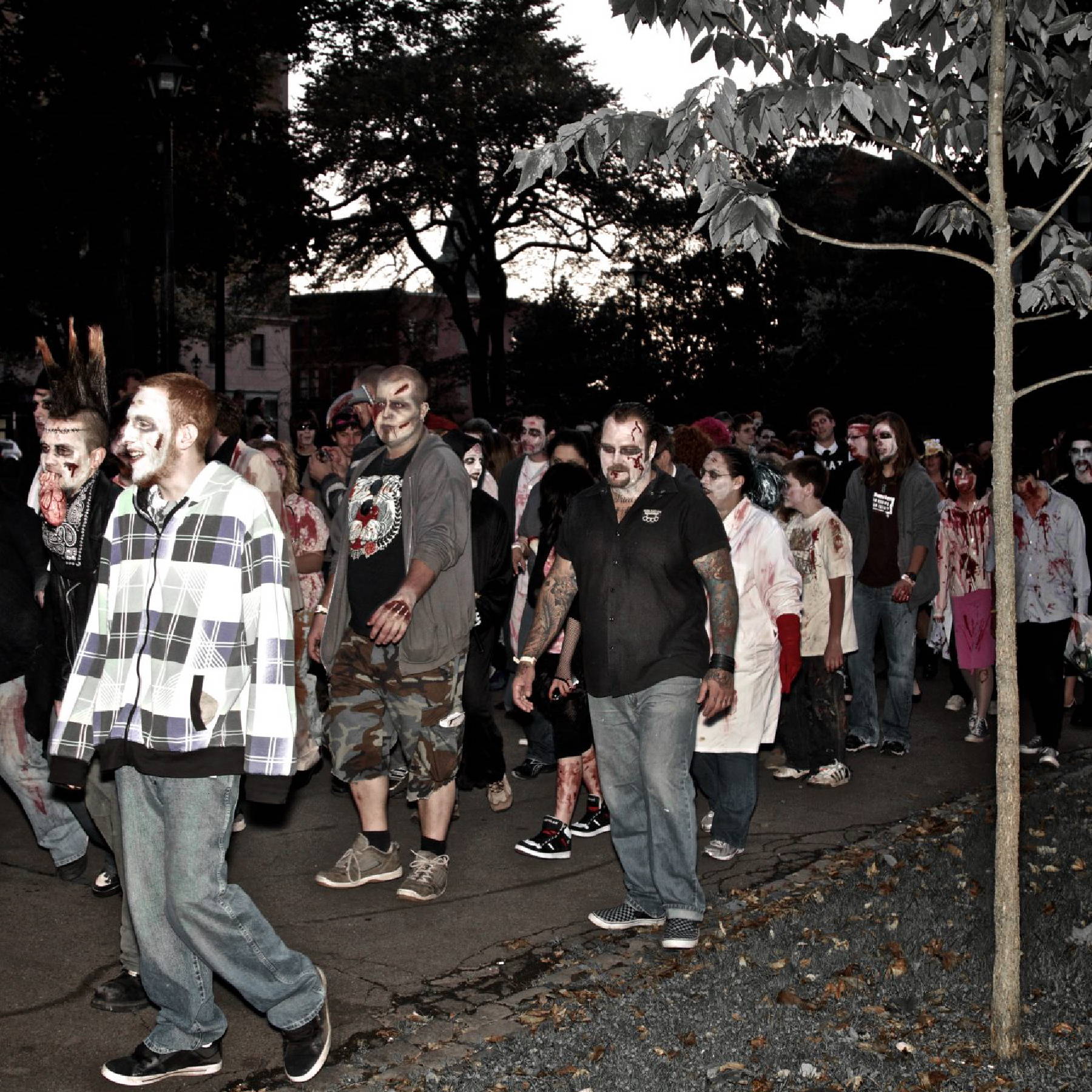 a group of people walking on a sidewalk dressed as zombies