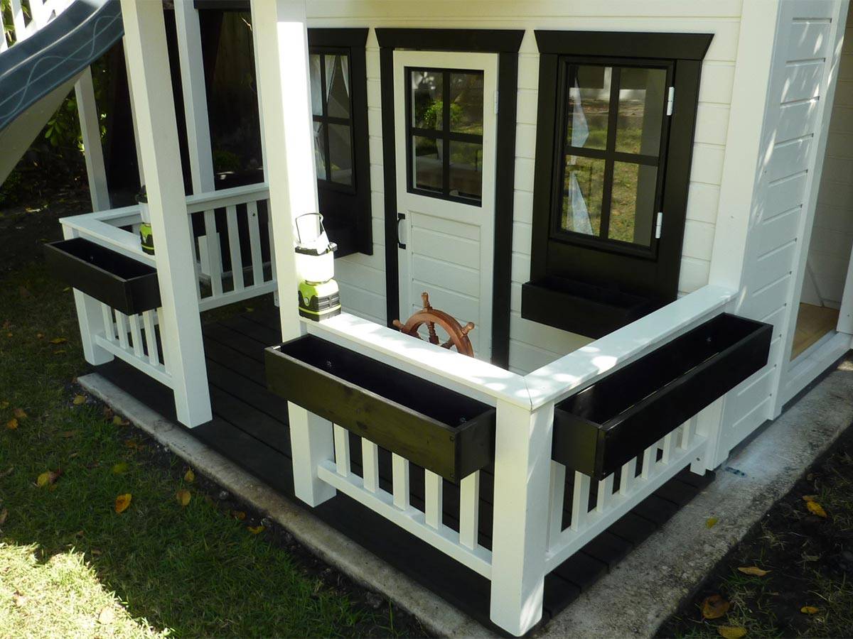 2-Story Outdoor Playhouse Prince close up of the wooden porch with white railing and black flower boxes, laterns and steering wheel by WholeWoodPlayhouses