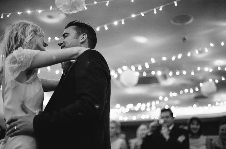 Bride and groom dancing together at their wedding surrounded by friends.