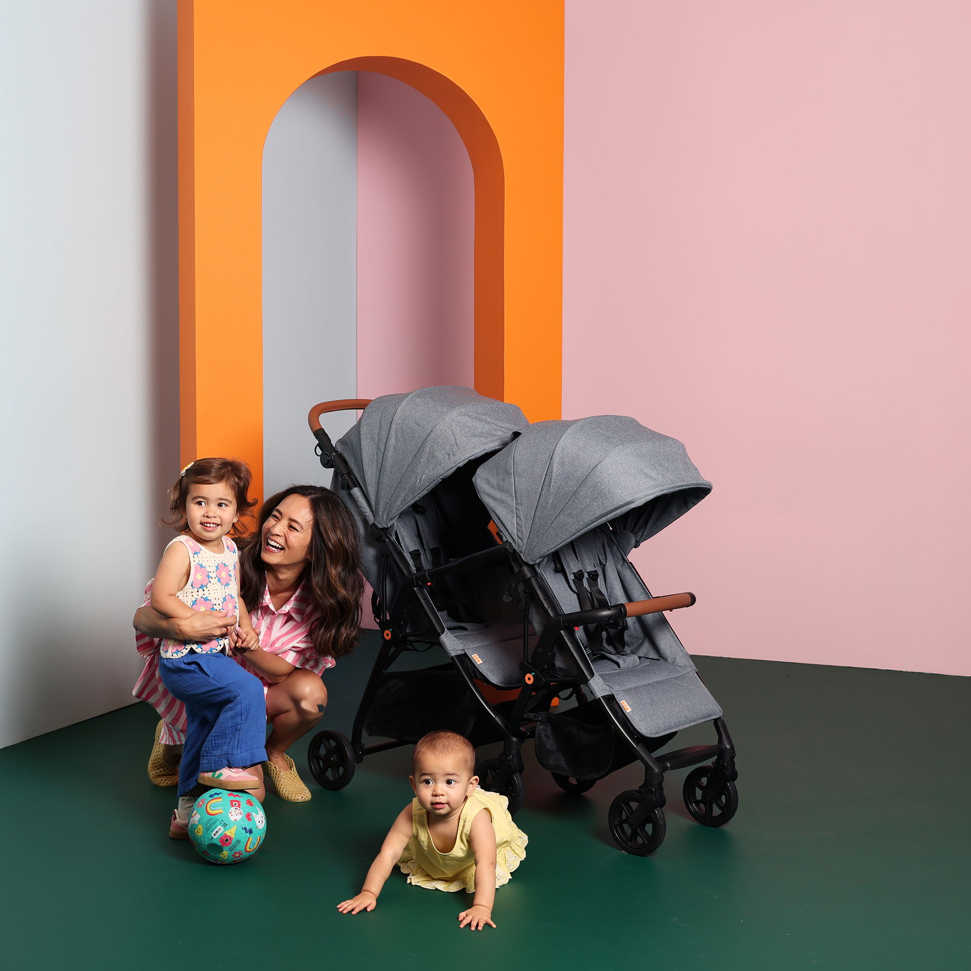 A woman with two children by a stroller in a colorful setting.