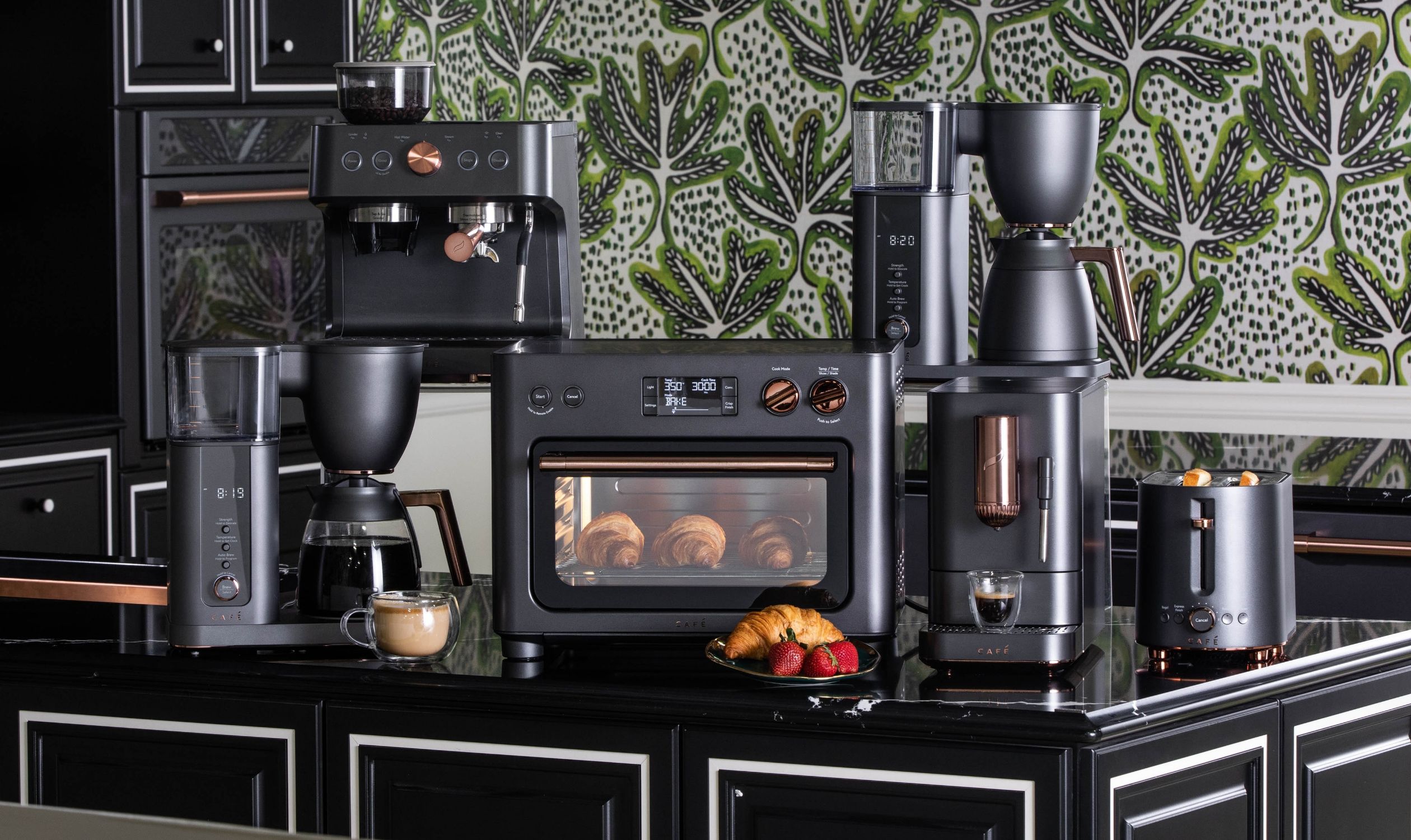 Matte black countertop appliances arranged on a counter with a patterned wallpaper background.