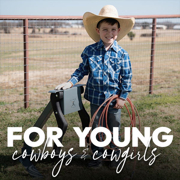 A young boy in cowboy attire holding a rope outdoors.