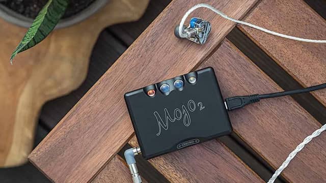 A portable audio device on a wooden surface with earphones.